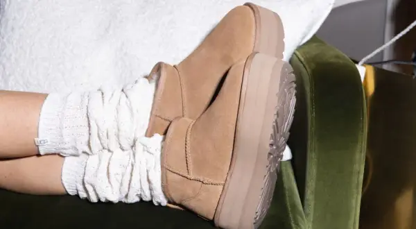 Pieds chaussés de bottes en daim UGG, avec des chaussettes blanches torsadées. Un aperçu de l'entretien chaussure daim.