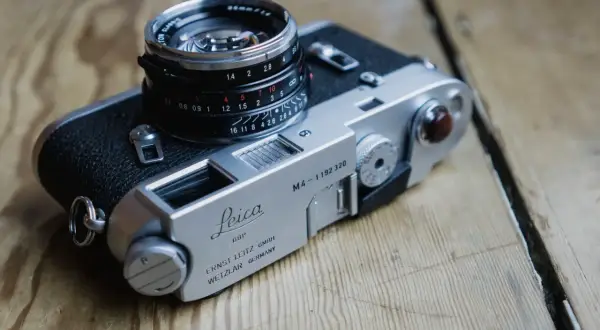 A classic Leica M4-P camera with a Summicron lens sits on a wooden surface.
