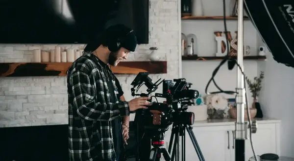 Operator z słuchawkami ustawia profesjonalną kamerę, gotową do nagrania wideo w wysokiej jakości, wykorzystując potencjał kodeka h265.