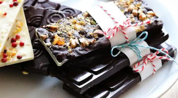 Selbstgemachte Schokolade: Dunkle Tafeln mit Nüssen und eine weiße mit Beeren und Früchten, bereit zum Genießen.