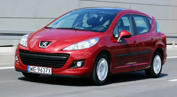 Czerwony Peugeot 207 na drodze. Wiele osób szuka peugeot 207 opinie, ten model jest świetnym wyborem.