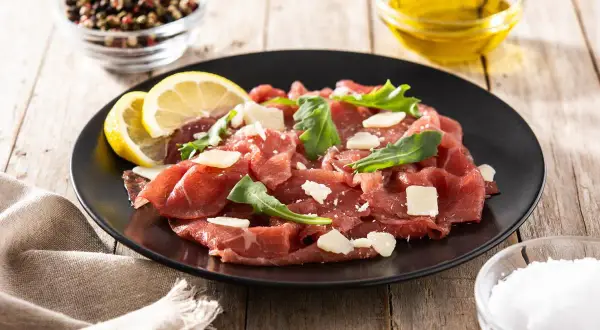 Carpaccio wołowe jak jeść: cienkie plastry surowej wołowiny z parmezanem, rukolą i cytryną. Idealne na lekki posiłek.