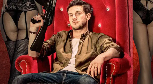 Mężczyzna z bronią na czerwonym tronie, otoczony przez kobiety w bieliźnie. Typowy plakat filmowy Patryka Vegi.