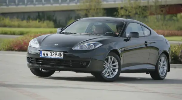Ciemnoszary Hyundai Coupe 2.7 V6 z brązową tapicerką, zaparkowany na zewnątrz.