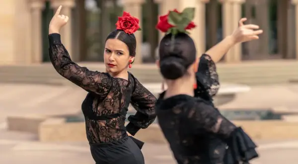 Una sevillana flamenca, con rosa roja en el pelo y pendientes a juego, baila con pasión.