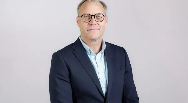 Ahlsell VD, en man med glasögon i mörkblå kavaj och ljusblå skjorta, ler mot kameran.