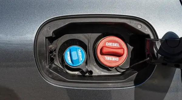 Dwa korki wlewu paliwa w samochodzie: czerwony z napisem DIESEL i niebieski z napisem AdBlue. To pokazuje, co to jest AdBlue.