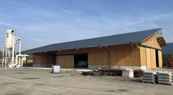 Nouveau bâtiment en bois, prêt à accueillir un atelier de menuiserie bois. Une tour de dépoussiérage est installée à côté.