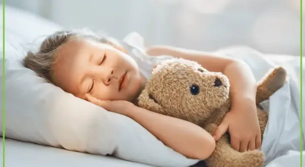 Spokojny sen dziecka z misiem. Melatonina dla dzieci wspiera zdrowy odpoczynek.