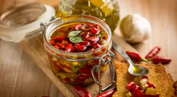 Peperoncino sott'olio con aglio, un tesoro piccante in un barattolo di vetro, pronto per insaporire ogni piatto.