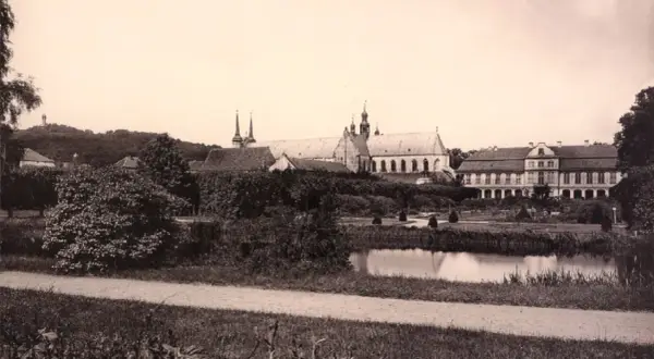Widok na pałac opatów w Gdańsku z ogrodem i stawem. W oddali wzgórze z pomnikiem.