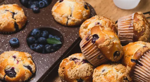 Pyszne muffinki z jagodami, niektóre w foremce, inne ułożone na desce. Ile piec muffinki?