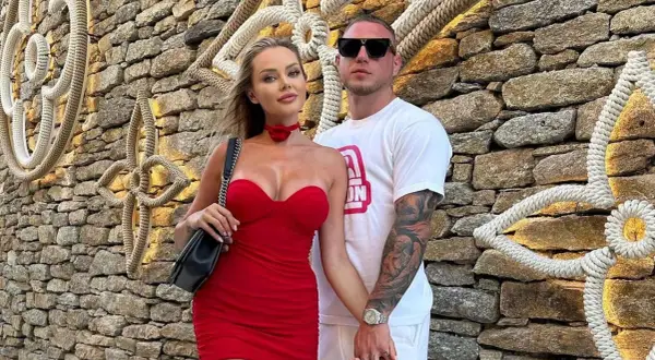 Ola Ciupa i Kubanczyk w czerwonych kreacjach pozują na tle kamiennej ściany z dekoracjami z liny.