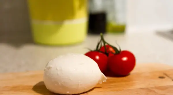Frische Mozzarella und Kirschtomaten auf einem Holzbrett. Perfekt für eine leichte Mahlzeit während der Schwangerschaft.