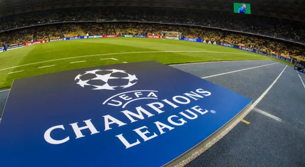 Logo Ligi Mistrzów UEFA na tle stadionu piłkarskiego.