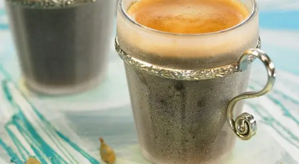 Dwie filiżanki kawy z pianką, obok strączki kardamonu. Zastanawiasz się, ile kardamonu do kawy dodać, by uzyskać ten aromat?