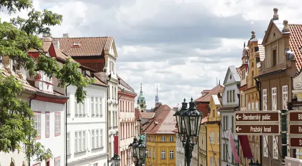 Urokliwa uliczka w Pradze, pełna kolorowych kamienic i zabytkowych latarni. Odkryj praskie nietypowe atrakcje, kierując się strzałkami do Zamku i Pałacu Sternbergów.