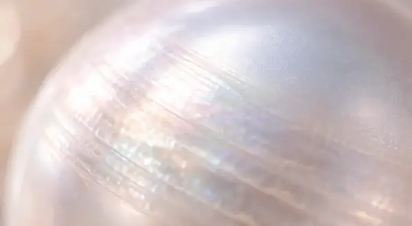 Detalle de una perla iridiscente, mostrando sus líneas naturales. Imagina limpiar perlas con bicarbonato para devolverles su brillo.