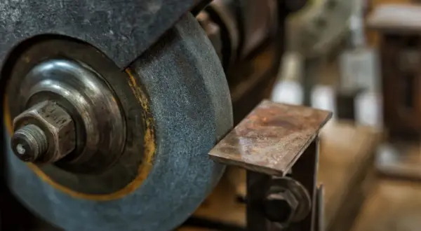 Zbliżenie na kamień szlifierski i metalowy element, pokazujące różne rodzaje kamieni szlifierskich w akcji.