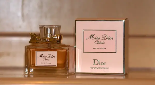 Elegancka butelka i pudełko perfum Miss Dior Chérie, ozdobione złotą kokardką, emanują luksusem.