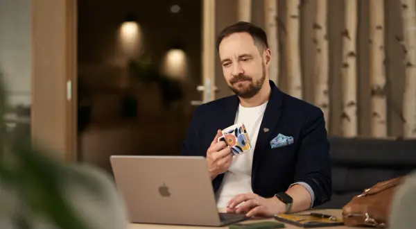 Man med kaffemugg vid laptop, funderar på firmabil regler.