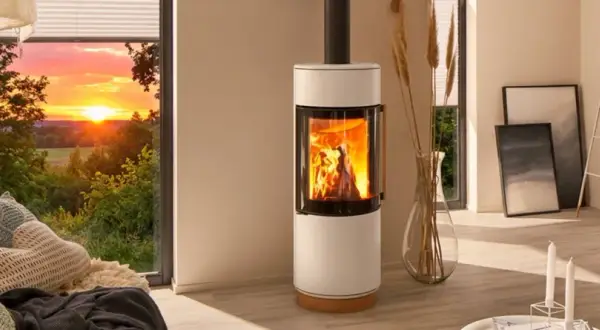 Gemütliches Wohnzimmer mit brennendem Kamin, der die Frage aufwirft: darf man im Sommer den Kamin anmachen? Sonnenuntergang draußen.
