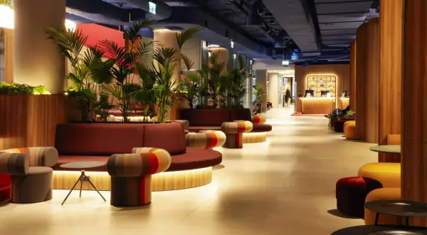 Nowoczesne wnętrze hotelu Mercure Warszawa Centrum z wygodnymi sofami, kolorowymi fotelami i bujną roślinnością.