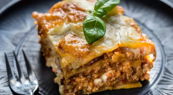 Une part de lasagne maison, dorée et gratinée, garnie de viande et de béchamel. Parfaite pour une recette lasagne réussie.