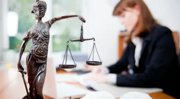 Statua della Giustizia con bilancia, avvocato al lavoro. Un successo per il ricorso invalidità civile vinto.