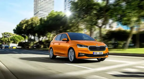 Pomarańczowa Skoda Fabia jedzie po mieście. Idealny samochód, by nauczyć się, co trzeba umieć na pierwszą jazdę.