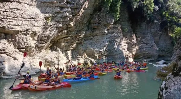 Gruppo in canoa esplora un canyon con pareti rocciose imponenti, navigando tra le marmitte dei giganti scavate dall'acqua.