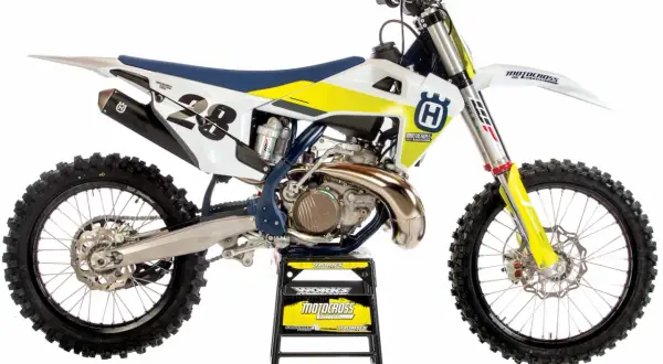 Motocykl Husqvarna 250 Enduro z numerem 28, biało-żółty, na czarnym stojaku.