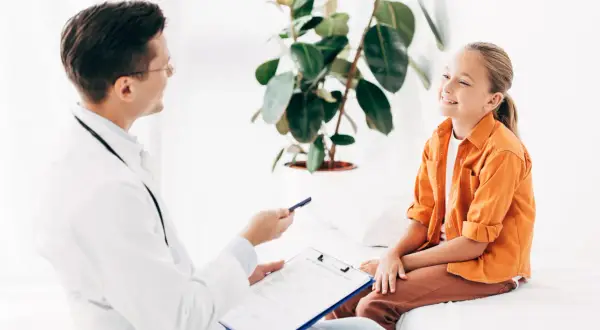 Lekarz rozmawia z uśmiechniętą dziewczynką o jej ADHD. Leczenie może przynieść ulgę i poprawić jakość życia.