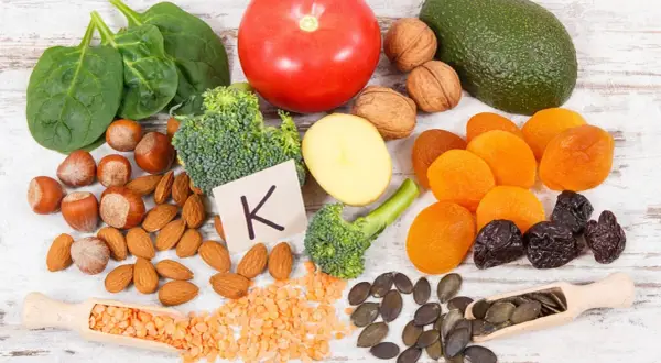 Gesunde Lebensmittel reich an Vitamin K, wichtig für die Schwangerschaft: Spinat, Brokkoli, Avocado, Nüsse, Trockenfrüchte.