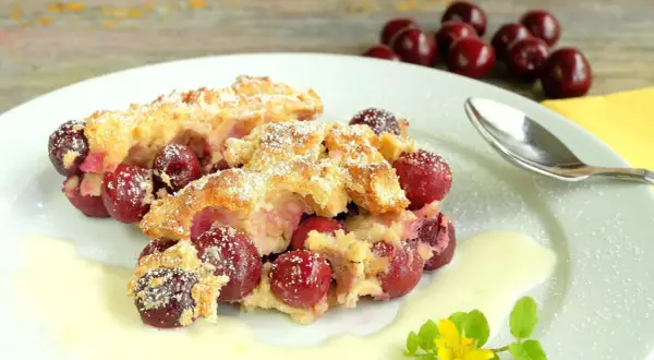 Zwei Portionen Kirschenmichel, ein köstliches Dessert, serviert mit Vanillesauce und bestäubt mit Puderzucker. Ein perfektes Kirschenmichel Rezept.