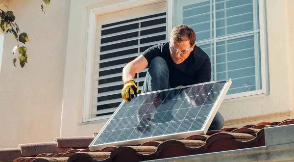 Hombre instala panel solar en tejado. ¡Qué frustración que mi comunidad no me deja poner placas solares!