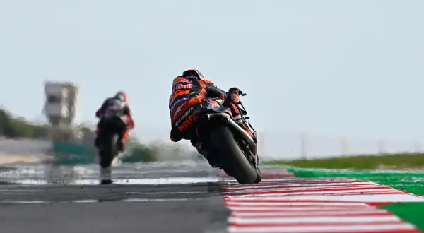Piloto de MotoGP inclinado en curva, luchando por la pole position en el qualy.