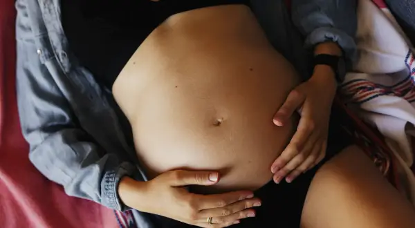 Ciężarna kobieta obejmuje brzuch. Może odczuwać ból pachwin w ciąży, ale skupia się na swoim maleństwie.