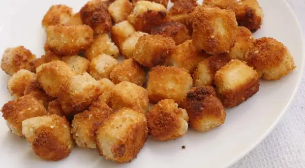 Krispiga, gyllene bitar av friterad tofu på en vit tallrik. Perfekt för ett snabbt och gott tofu recept.