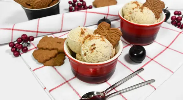Leckeres Spekulatius Eis selber machen? Hier sind zwei Schalen mit cremigem Eis, garniert mit Spekulatius und roten Beeren.