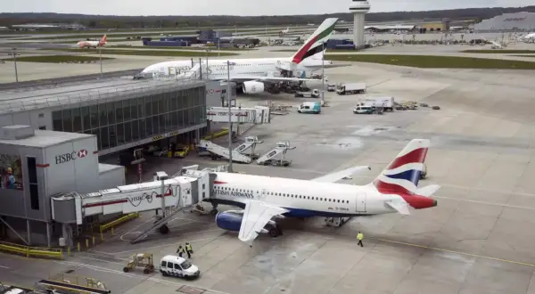Samoloty British Airways i Emirates na lotniskach w Londynie. W tle wieża kontroli lotów.