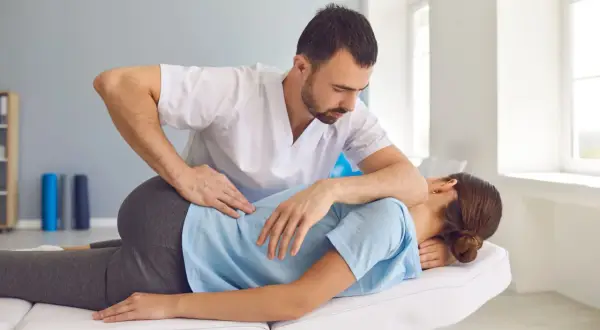 Fizjoterapeuta wykonuje terapię manualną, uciskając plecy pacjentki. To pokazuje, na czym polega terapia manualna – na pracy z ciałem.