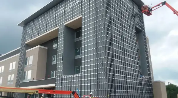 Instalación de sistemas de fachadas ventiladas en edificio moderno. Obreros en plataformas elevadoras trabajan en la colocación de paneles.