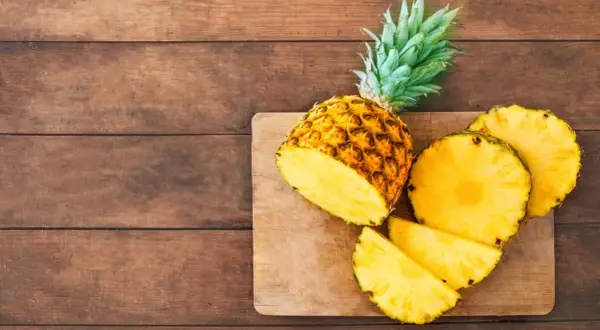 Saftige Ananas, frisch aufgeschnitten, liegt auf einem Holzbrett. Eine gesunde Wahl, die an den Geschmack von Ananas aus der Dose erinnert.