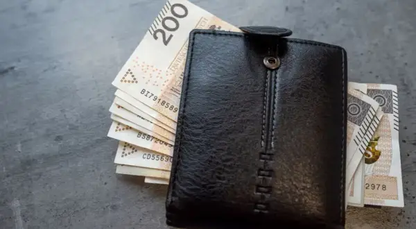 Czarny portfel z polskimi banknotami. Zastanawiasz się, jak obliczyć chorobowe w ciąży? Finanse przyszłej mamy.
