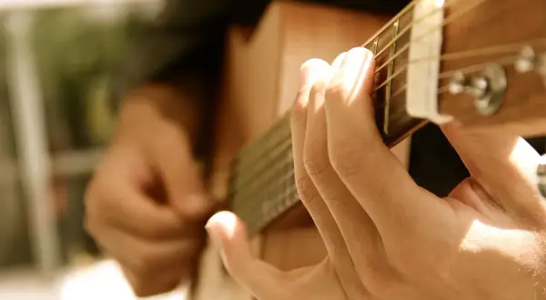 Dłonie grające na gitarze, tworząc dźwięki, które mogą wywołać uczucie lacrimosa.
