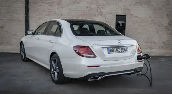 Un Mercedes 300de blanco, con el distintivo "E 300de", está enchufado a un cargador eléctrico.