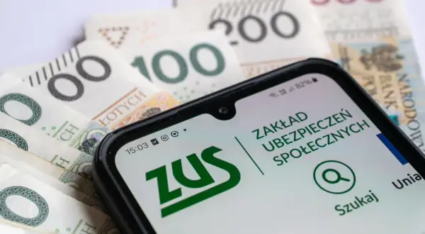 Telefon z aplikacją ZUS na tle polskich banknotów. Ubezpieczenie społeczne w zasięgu ręki.