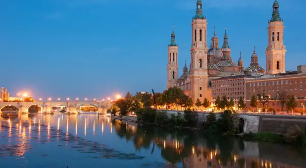 Bazylika w Saragossie i most nad rzeką Ebro o zmierzchu. Idealne miejsce na tanie hiszpania loty.