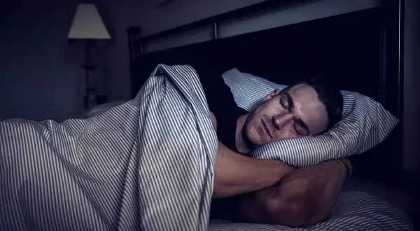 Man sleeping soundly, embracing deep sleep for optimal muscle recovery.